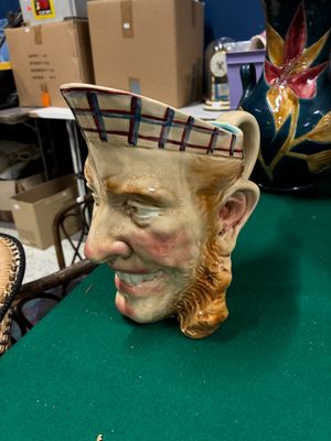 une statue représentant un homme fumant la pipe à côté d'un vase