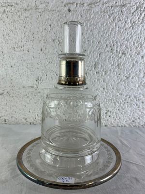 une bouteille en verre avec un bouchon argenté posée sur une assiette