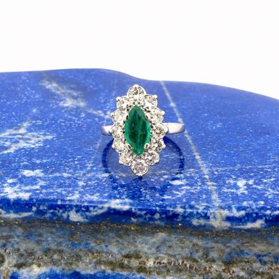 an oval emerald and diamond cluster ring on a blue stone