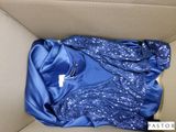 une chemise bleue dans une boîte en carton sur laquelle est accrochée une étiquette