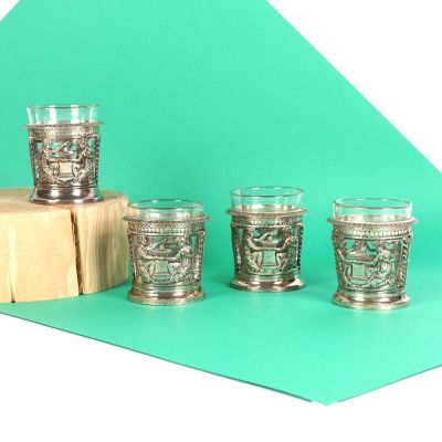 six verres à shot en argent posés sur une table, à côté d'un bloc en bois