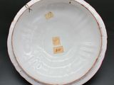 an old white plate with a red rim and a brown rim