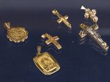 plusieurs pendentifs en forme de croix, en or et en argent, sur un fond noir