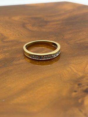 une photo d'une bague en or sertie de diamants noirs posée sur une table en bois