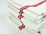 stack of four white towels with red stripes on them on a white surface