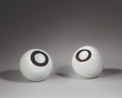two white balls with black circles on them on a white surface
