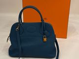 a blue handbag with orange box on a white surface