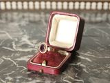une petite boîte rouge contenant une bague, posée sur une table