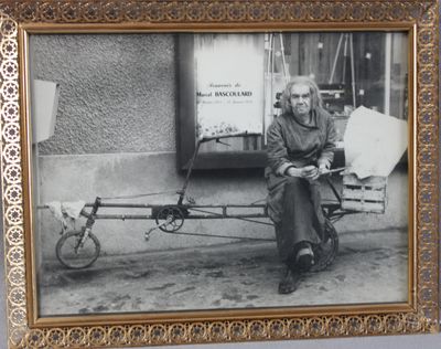 une vieille photo d'un homme assis sur un banc auquel est attaché un vélo