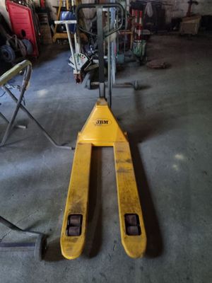 un chariot élévateur dans un garage, avec d'autres outils en arrière-plan