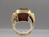 a close up of a ring with a red stone in it