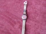 a watch that is laying on a pink surface