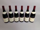 six bouteilles de vin sont alignées sur une table