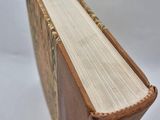 an old book is sitting on a white surface with a white background