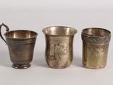 three silver cups are lined up next to each other on a white surface