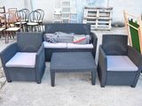 un canapé, un fauteuil, un pouf et une table basse dans un jardin