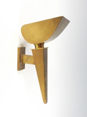 brass sconce wall light with a triangular shape on a white wall