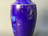 a blue vase sitting on a table with a white wall in the background