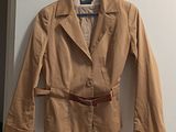 brown jacket with belt on hanger on white wall in room
