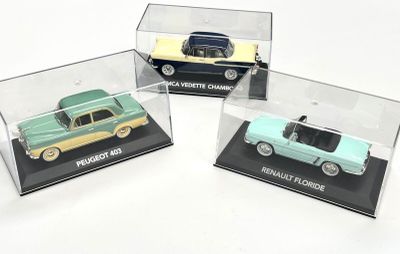 trois voitures miniatures dans une vitrine posée sur une surface blanche