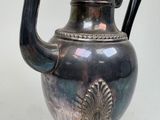 a silver vase with a black handle on a table