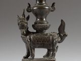 un vieux vase en bronze posé sur un socle orné d'un oiseau