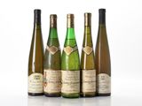 quatre bouteilles de vin sont alignées sur une surface blanche