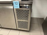 a stainless steel refrigerator in a kitchen with a blue sign on it