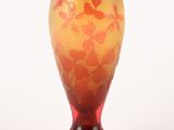 un vase rouge et jaune posé sur une surface blanche