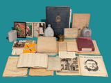 de nombreux livres anciens posés sur une table, à côté d'une bouteille d'eau