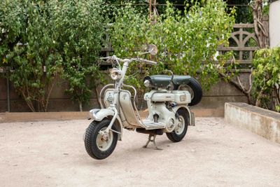 a small motor scooter that is parked in front of a fence