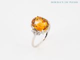 une image représentant une bague ornée d'une grosse citrine entourée de diamants