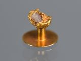 a gold ring with a stone in it on a stand