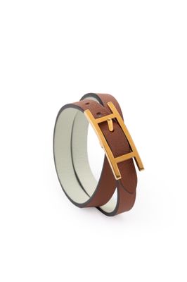 un gros plan sur un bracelet en cuir marron muni d'une boucle dorée