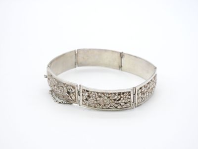 gros plan d'un bracelet en argent sur une surface blanche