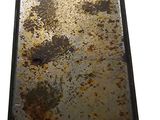 a metal tray with rust on it on a white surface