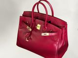 Le sac à main en cuir rouge est posé sur une surface blanche.