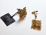 deux paires de boucles d'oreilles en or représentant un livre et une croix sur un fond blanc