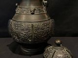 a large metal vase and a small metal container