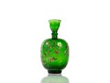 a green glass bottle with a gold design on it
