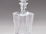 une carafe en verre transparent posée sur une surface blanche, avec une ombre au sol