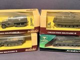 three boxed boxed toys of military vehicles on display on a gray surface