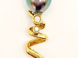 une image représentant un pendentif composé d'une perle noire et de diamants, sur fond blanc