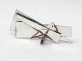 a silver and red brooch on a white surface