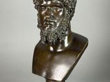 a bronze bust of a man with curly hair and beard