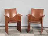 deux fauteuils en cuir marron placés l'un à côté de l'autre sur un sol à carreaux