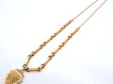 a close up of a gold necklace with a heart pendant on it