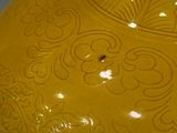 a yellow vase with a design on it on a table