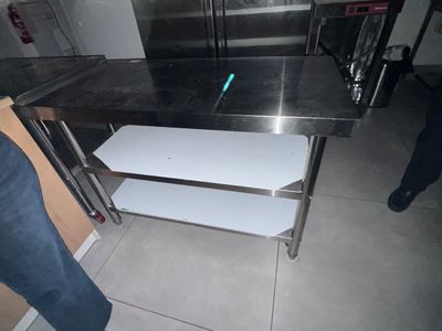 une table en acier inoxydable comportant deux étagères