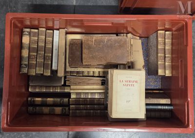 une boîte rouge remplie de vieux livres, posée par terre